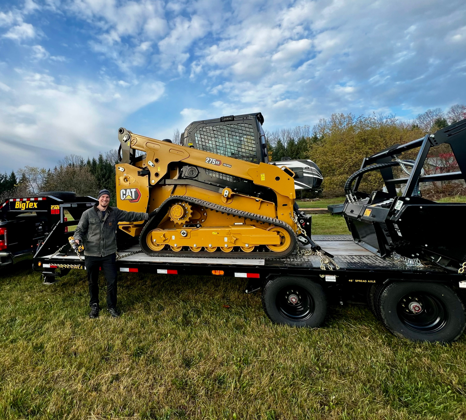 Owner of Truax Land Clearing standing next to CAT 275XE skid steer on trailer in Northeast Wisconsin